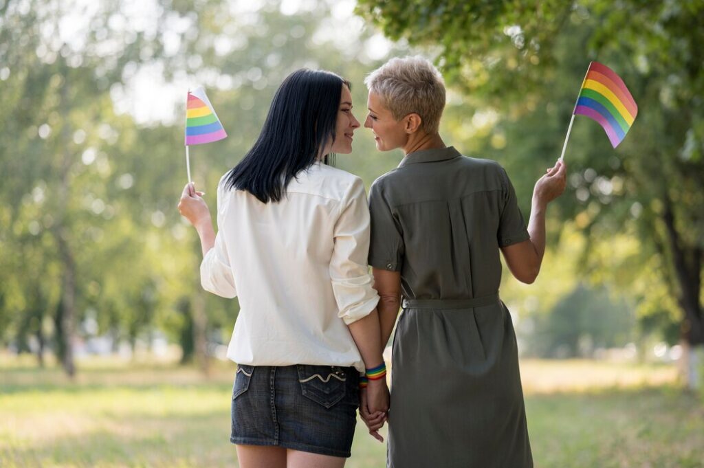 Two lesbian-identifying women appear with pride flads